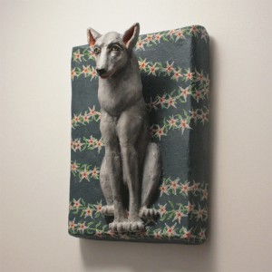 sitzender Wolf auf dunkelblaugrauem Untergrund auf dem sich sternförmige Blüten ranken. Dreiviertel Ansicht von links.